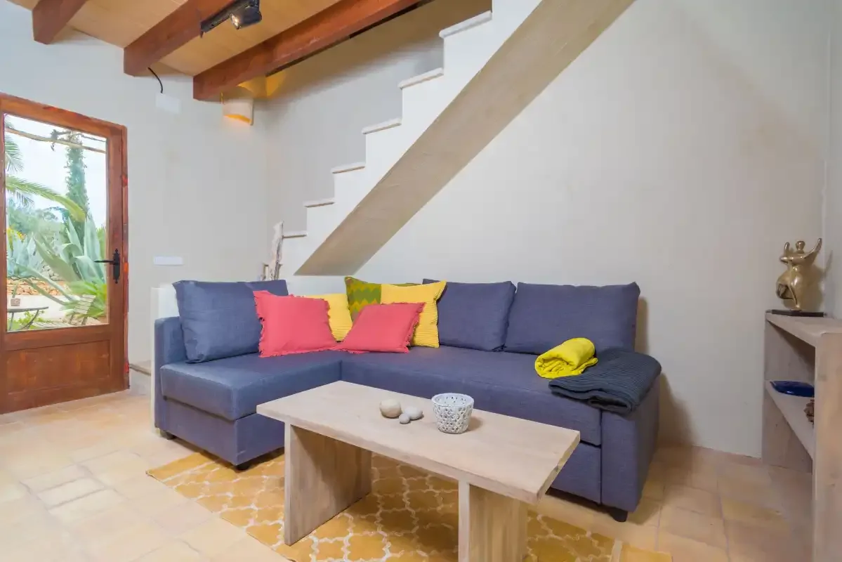Una sala de estar con asientos en esquina bajo una escalera.
