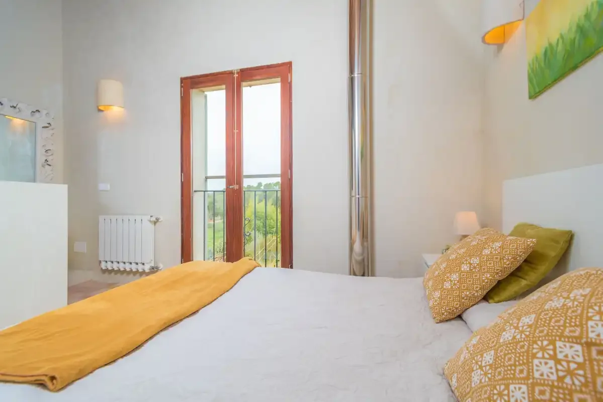 Un dormitorio con una cama junto a puertas de vidrio altas que dan a un balcón.