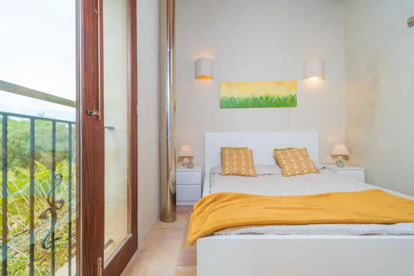 Un dormitorio con una cama, mesitas de noche y una puerta de cristal que da a un balcón.