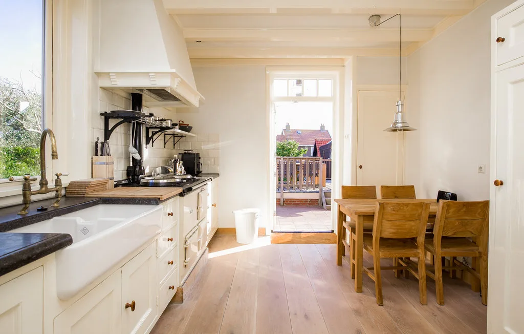 Una luminosa cocina con comedor, una encimera larga y una mesa de madera.