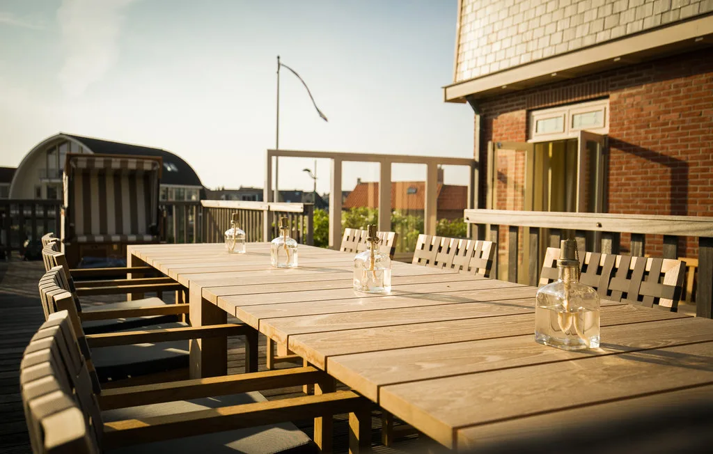 Una zona de comedor en una azotea con una mesa larga de madera y sillas.