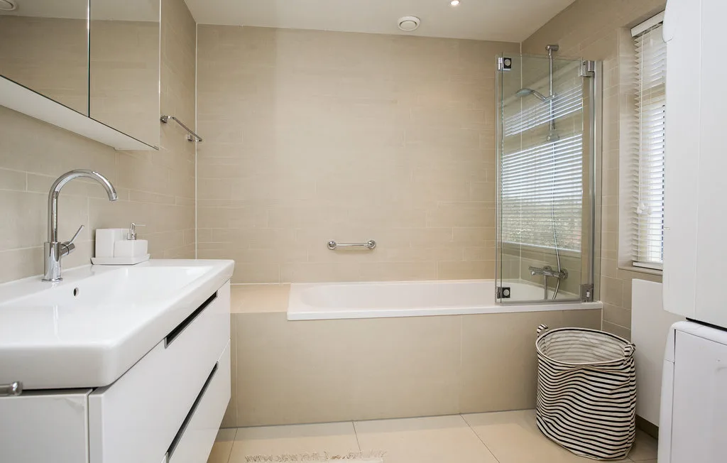 Un baño luminoso con bañera, mampara de vidrio y lavabo.