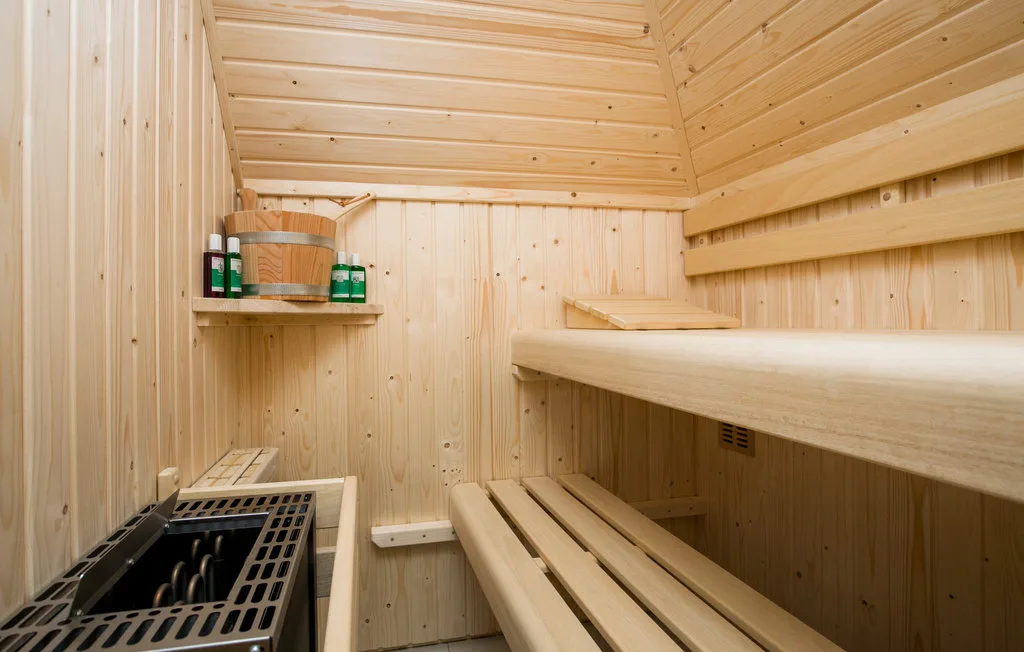 Una sauna revestida de madera con bancos escalonados y un calentador.