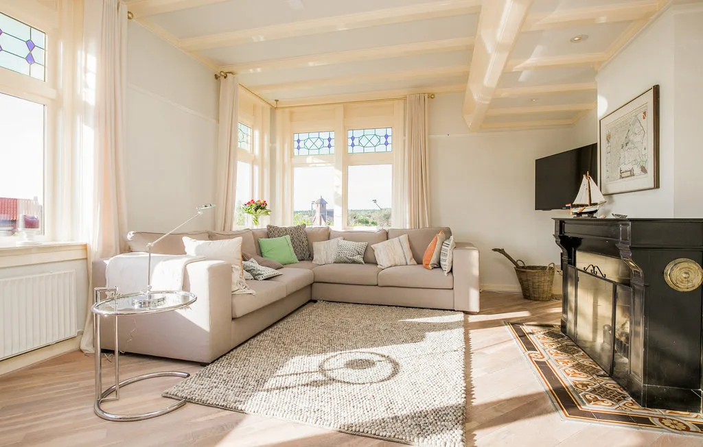 Una sala luminosa con un sofá seccional y una chimenea.