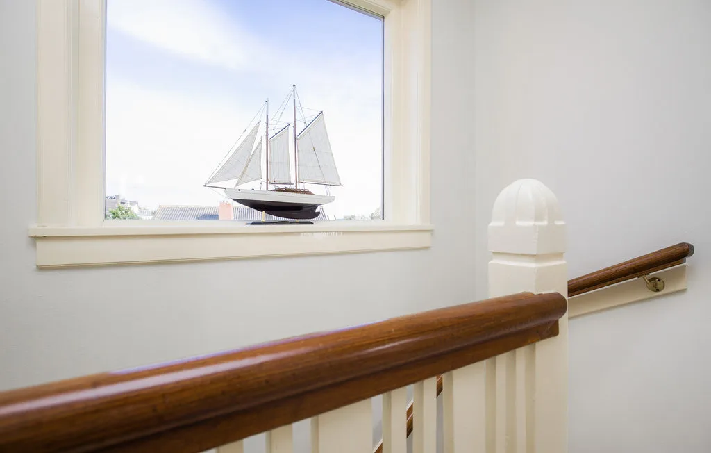 Una escalera con pasamanos de madera da a un velero por la ventana.