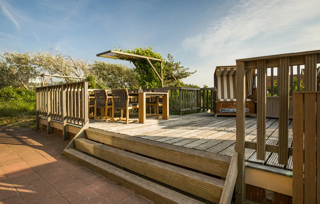Una terraza exterior de madera con una mesa de comedor y asientos.