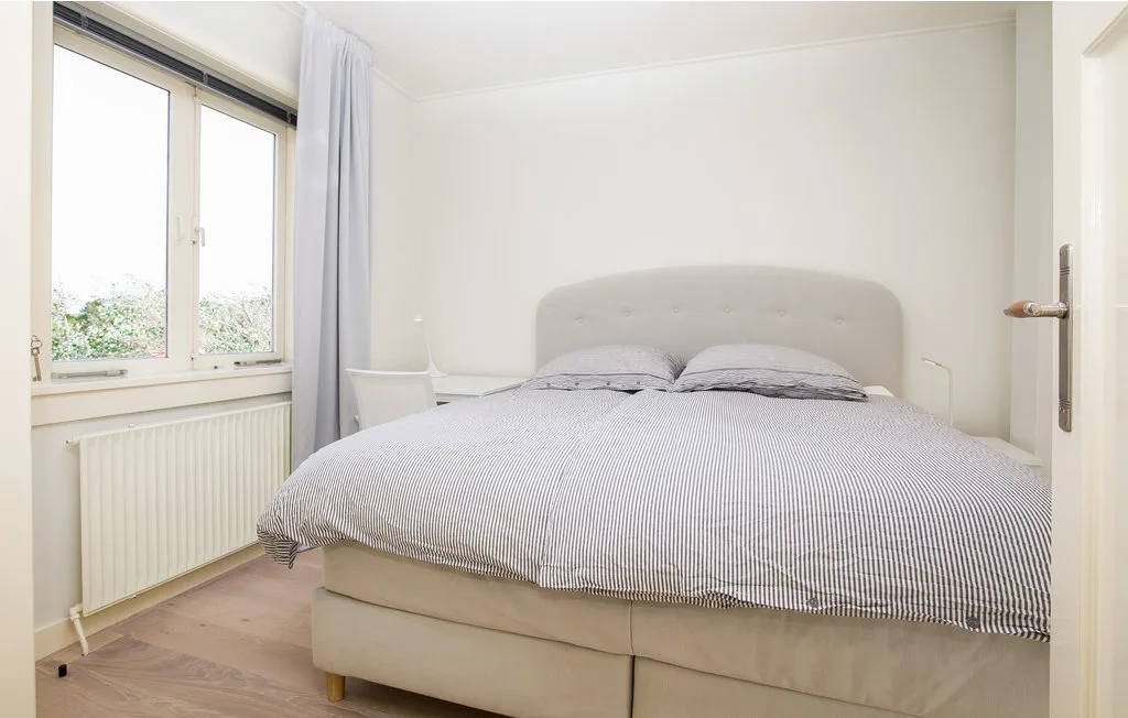 Un dormitorio luminoso con una cama grande junto a una ventana.