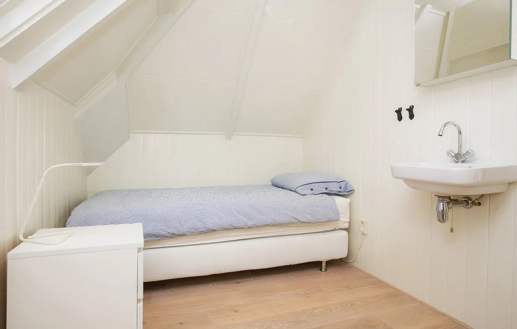 Un dormitorio pequeño con una cama individual y un lavabo de pared.
