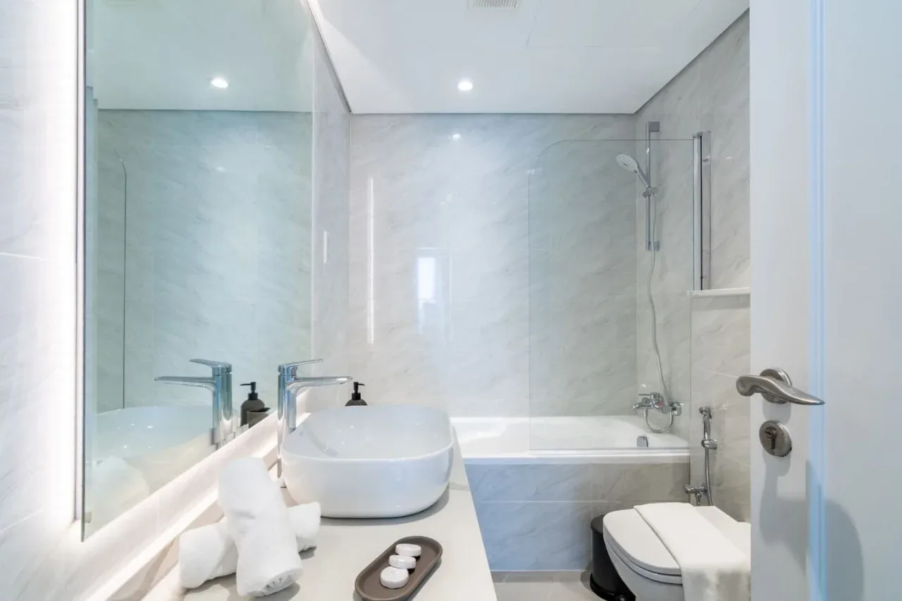 Un baño luminoso con bañera, ducha, lavabo e inodoro.