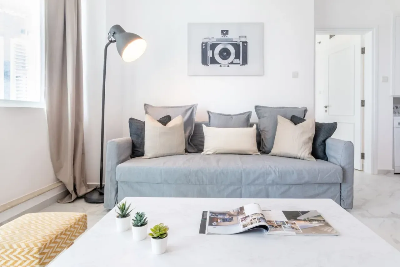Una sala luminosa con sofá, lámpara de pie y mesa de centro.