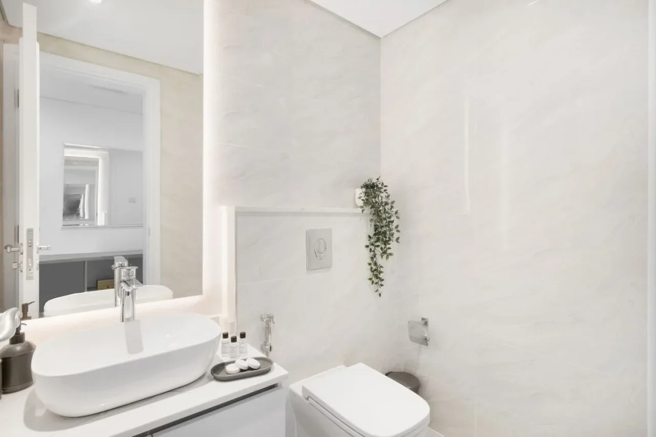 Un baño luminoso con lavabo, inodoro y paredes de tonos claros.