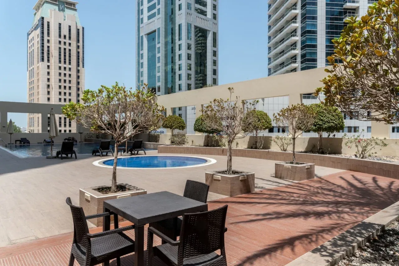 Una terraza al aire libre tiene asientos, jardineras y una pequeña piscina redonda.