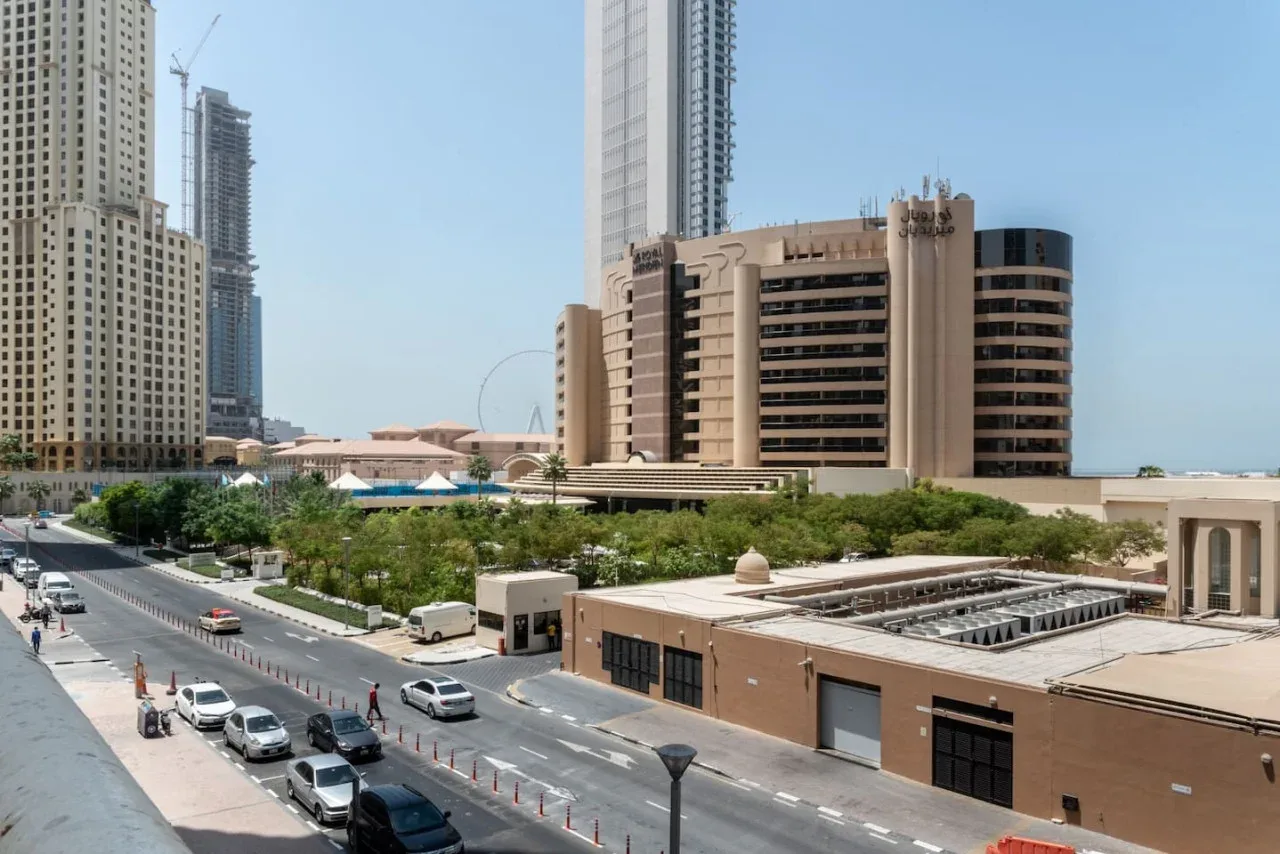 Una calle urbana bordea edificios modernos de gran altura y áreas ajardinadas.