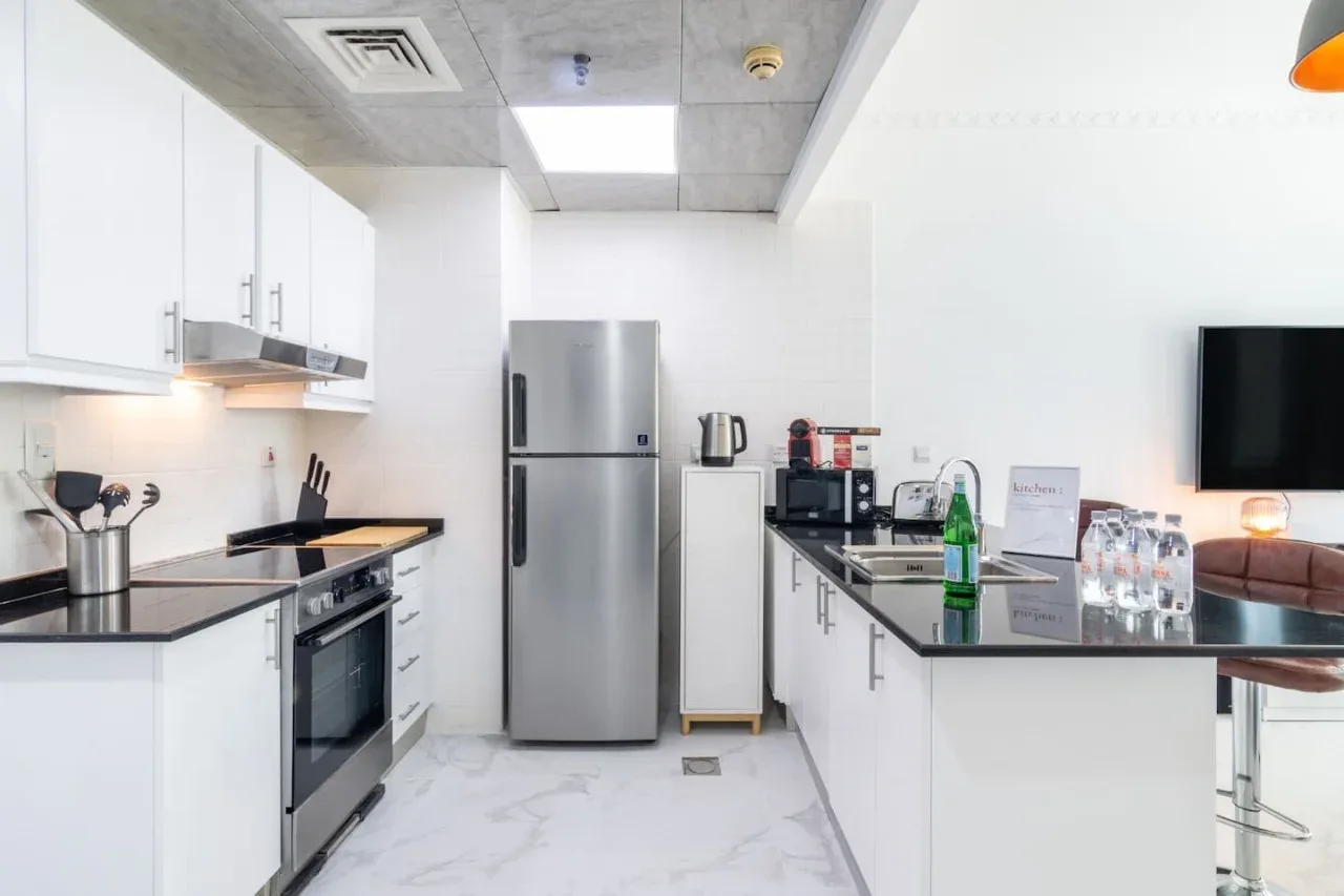 Una cocina moderna y luminosa con gabinetes blancos, electrodomésticos de acero inoxidable y una encimera.