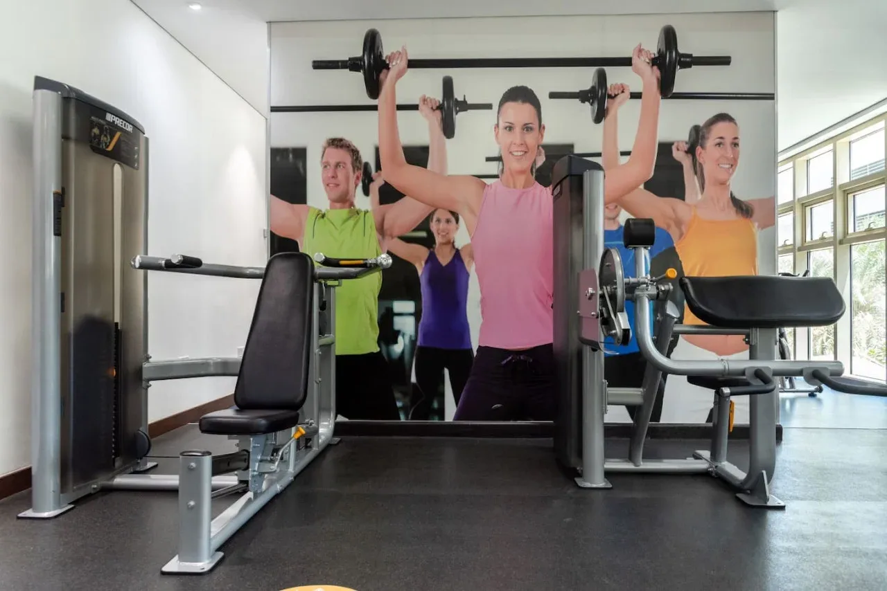 Una sala de entrenamiento luminosa con personas haciendo ejercicio en máquinas de pesas.