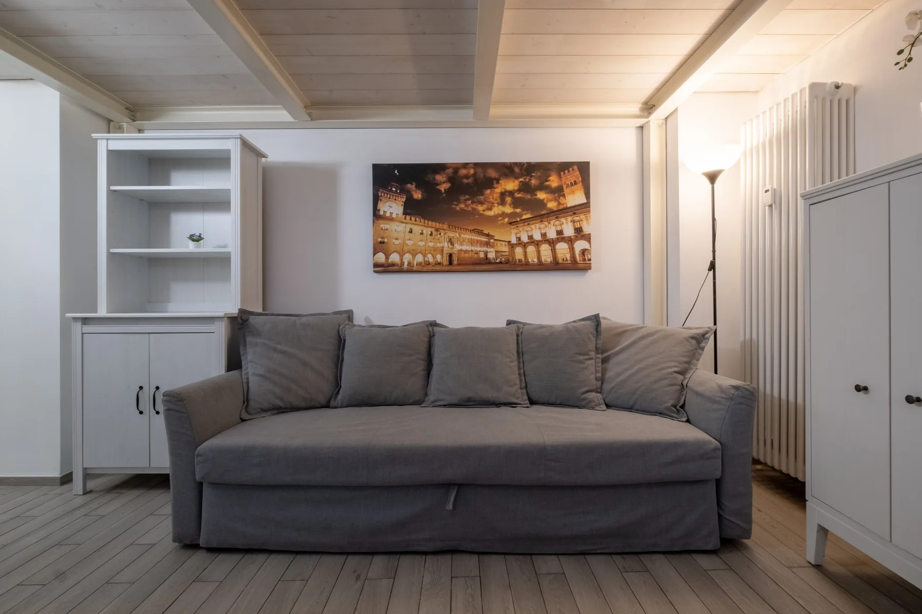 A living room with gray seating beneath a framed cityscape.
