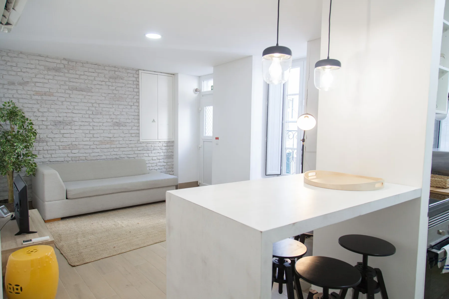 A bright living area with a sofa and a white kitchen island with stools.