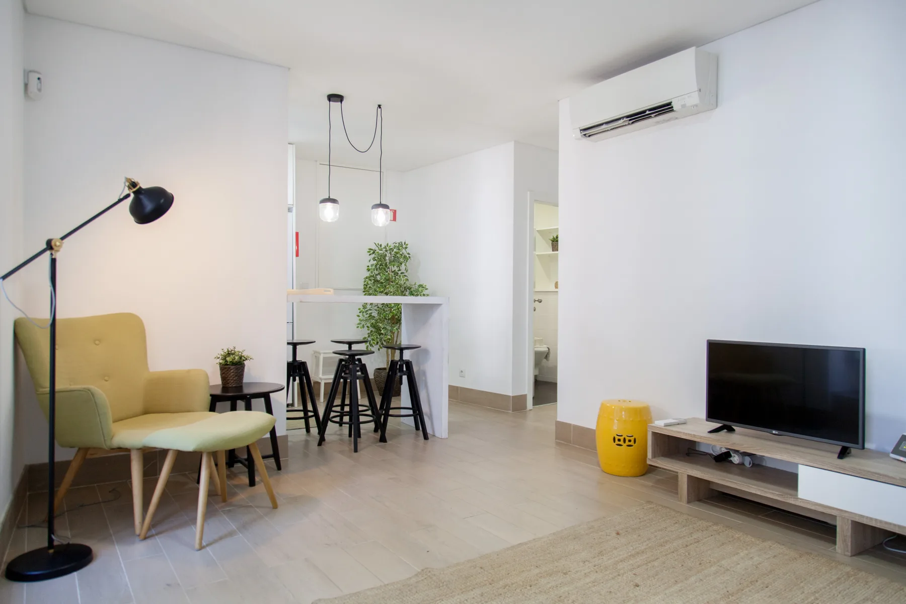 A living area with seating, a dining counter, and a television.