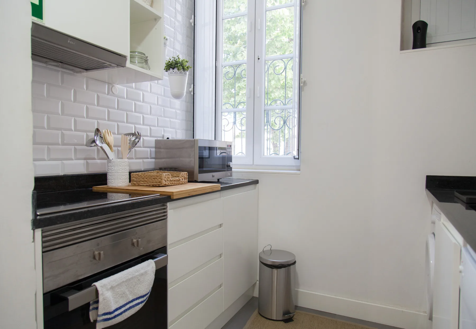 A bright kitchen with white cabinets and a tall window.