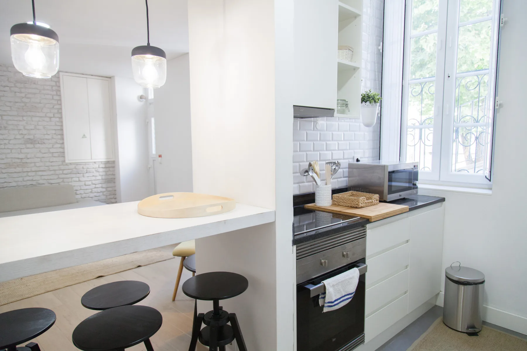 A bright kitchen with a white breakfast counter and large windows.
