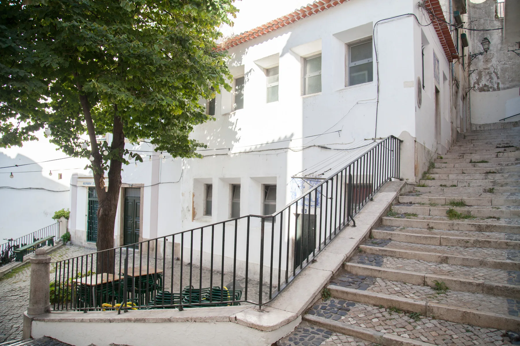 White residential buildings line an outdoor stone stairway beneath leafy trees.