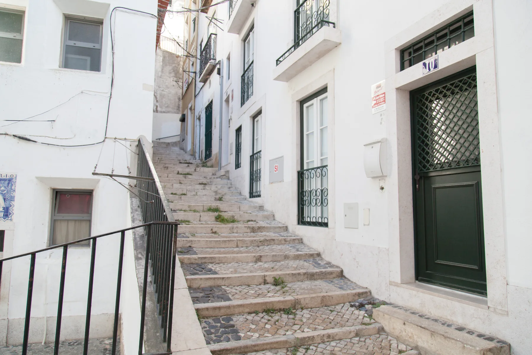 A narrow stone stairway climbs between white buildings along a quiet-looking street.
