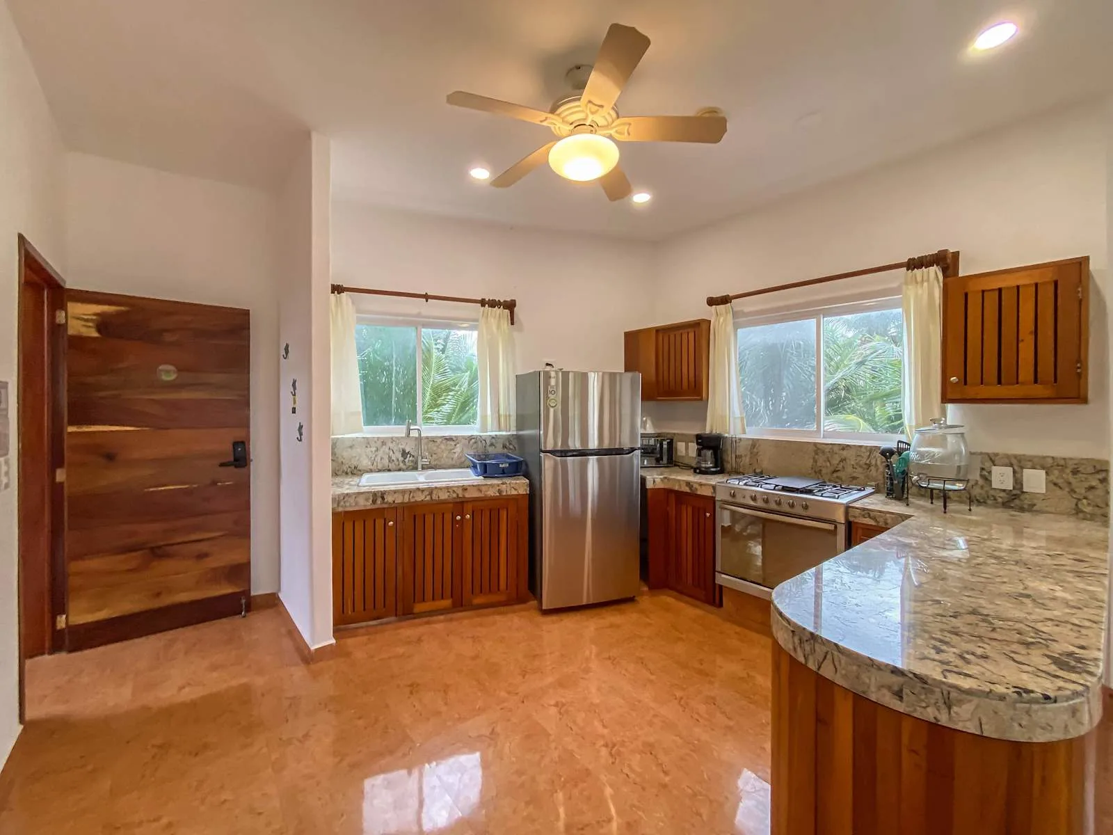 Una cocina luminosa con gabinetes de madera, un refrigerador y una encimera curva.