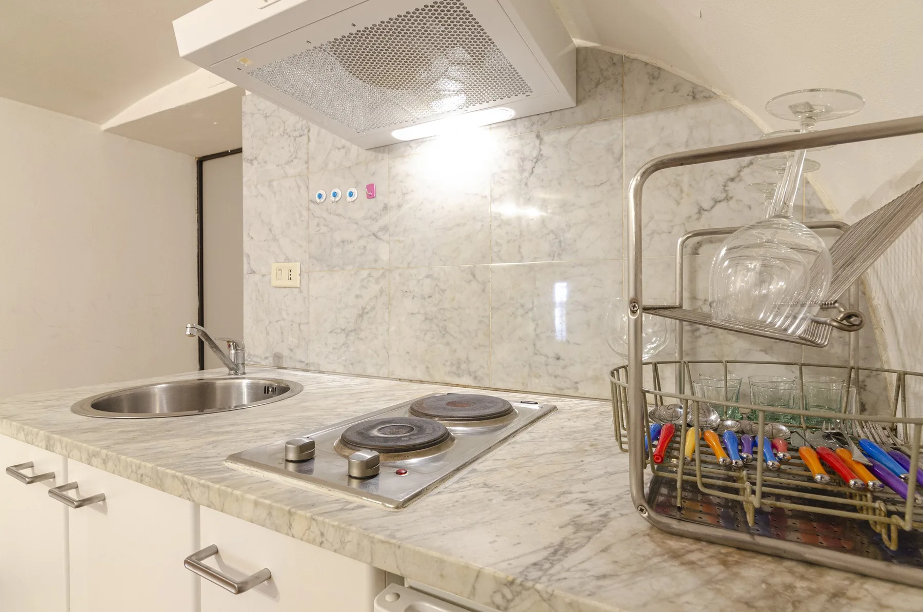 Una encimera de cocina compacta con fregadero, placa de cocción y escurridor.
