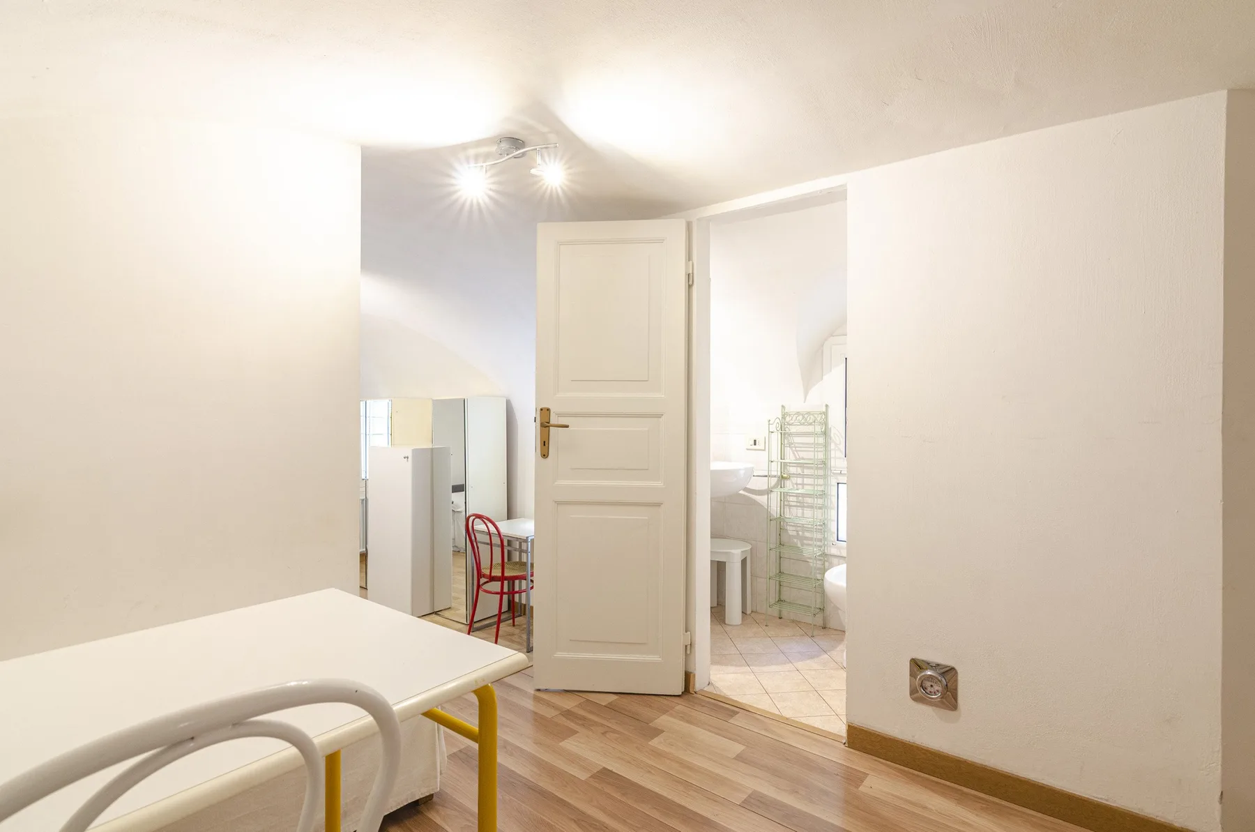 Una habitación luminosa con una cama y una puerta abierta que da a un baño.
