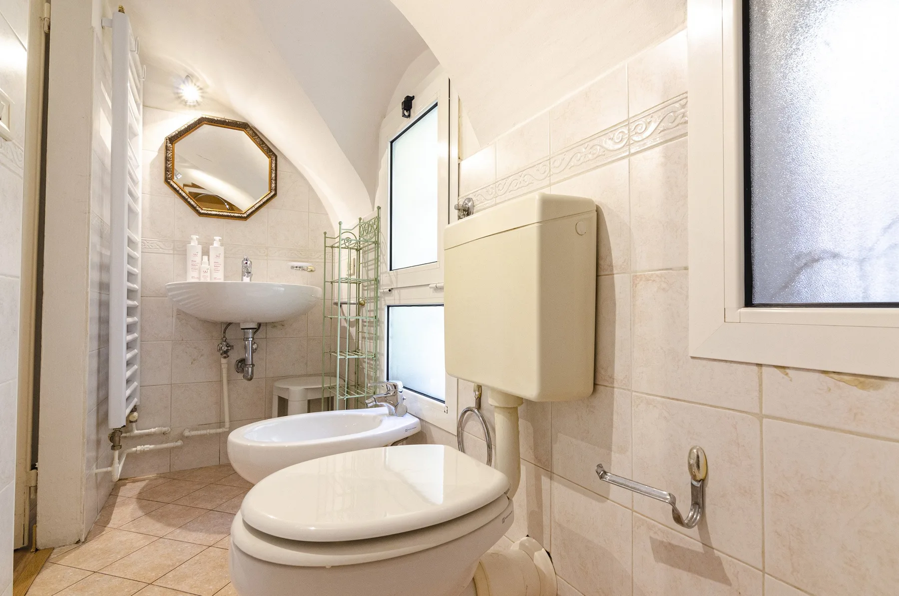 Un baño con azulejos, inodoro, bidé y lavabo suspendido.