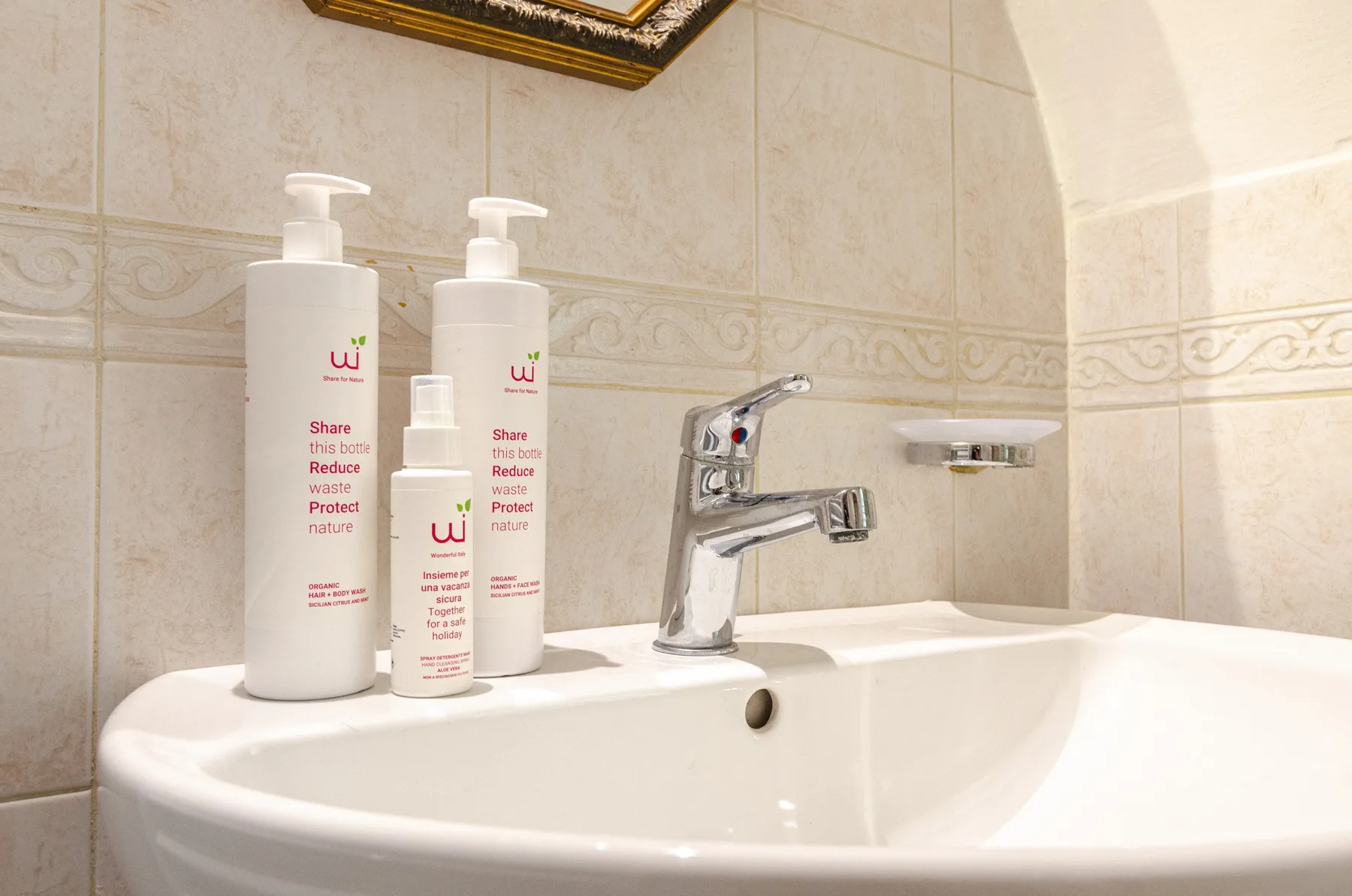 Un lavabo de baño con grifo cromado y varios frascos con dosificador en el borde.