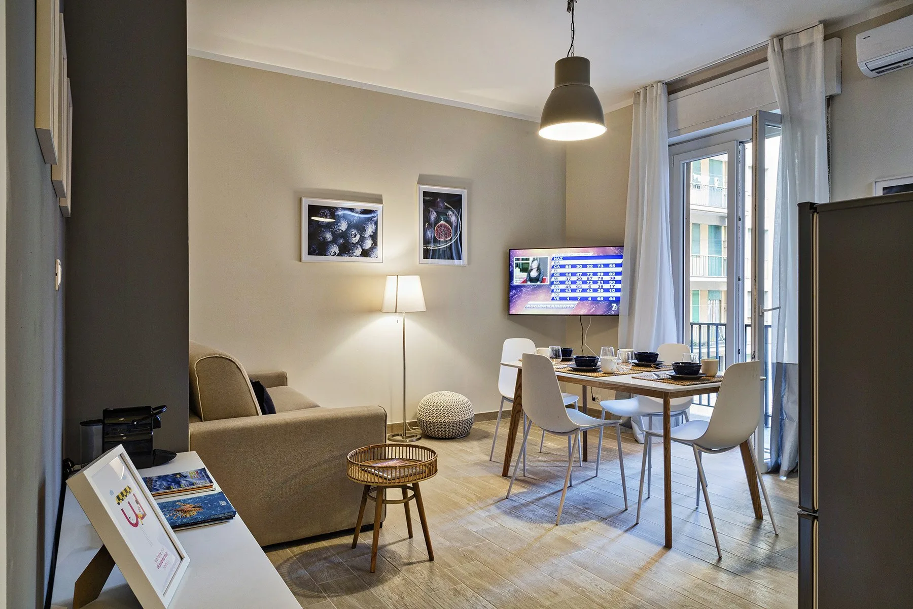 A living and dining area with a sofa, table, and large windows.