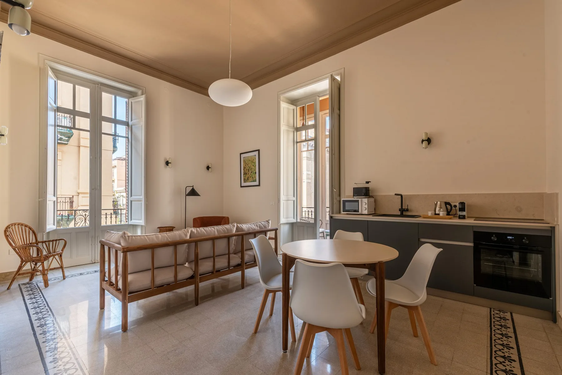 A bright living and dining area with a sofa, table, and kitchenette.