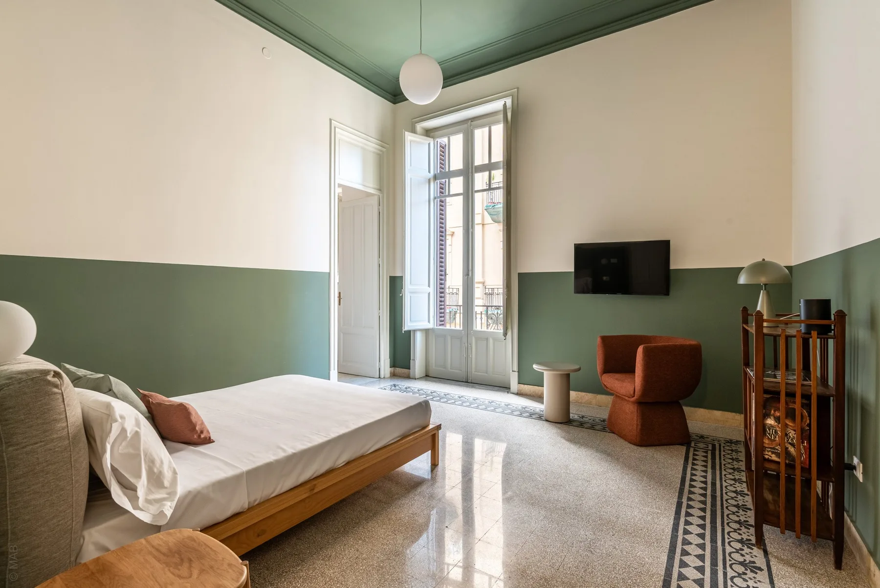 A bedroom with a low bed and a television mounted on the wall.