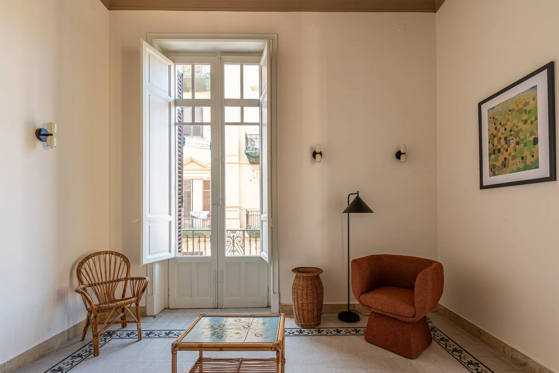 A bright sitting room with tall windows and a small seating area.