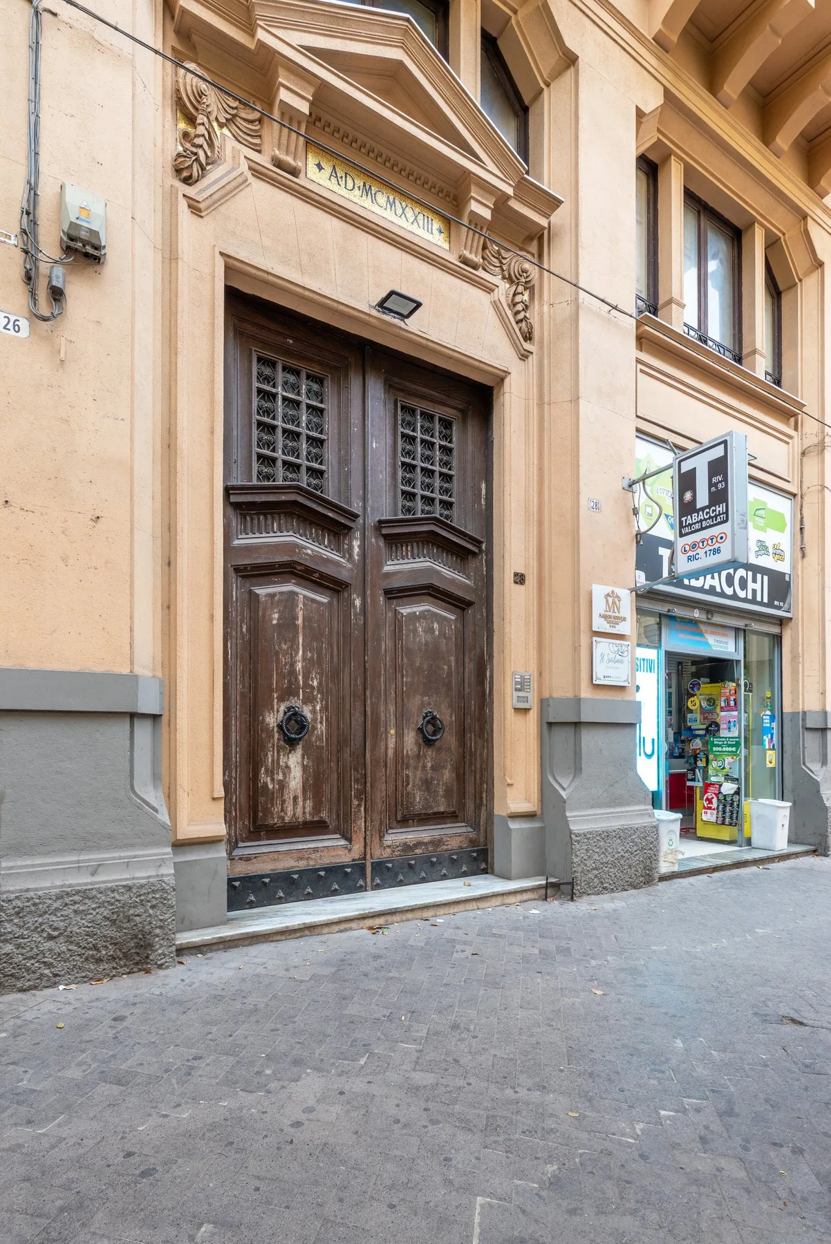 A street-facing building entrance with tall ornate wooden double doors.