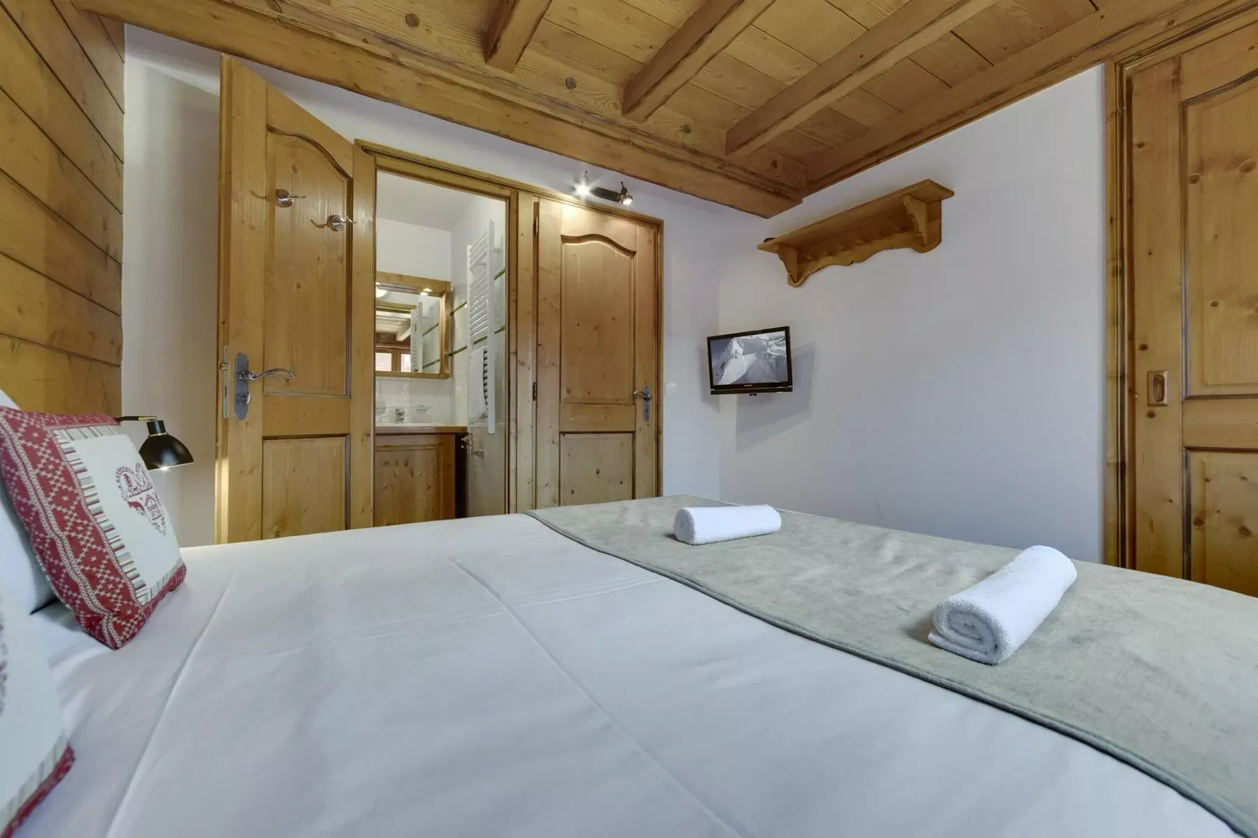Un dormitorio con una cama bien hecha y puertas de madera.