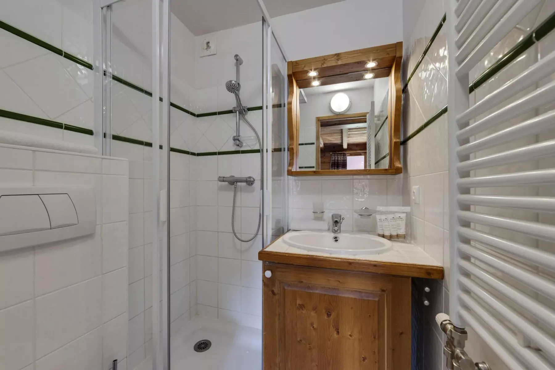 Un baño compacto con ducha de cristal, lavabo y mueble de madera.