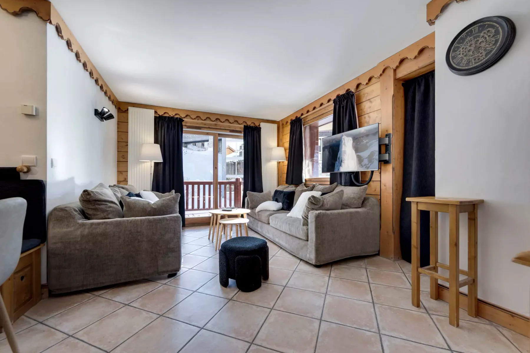Living room with seating, a television, and windows opening onto a balcony.