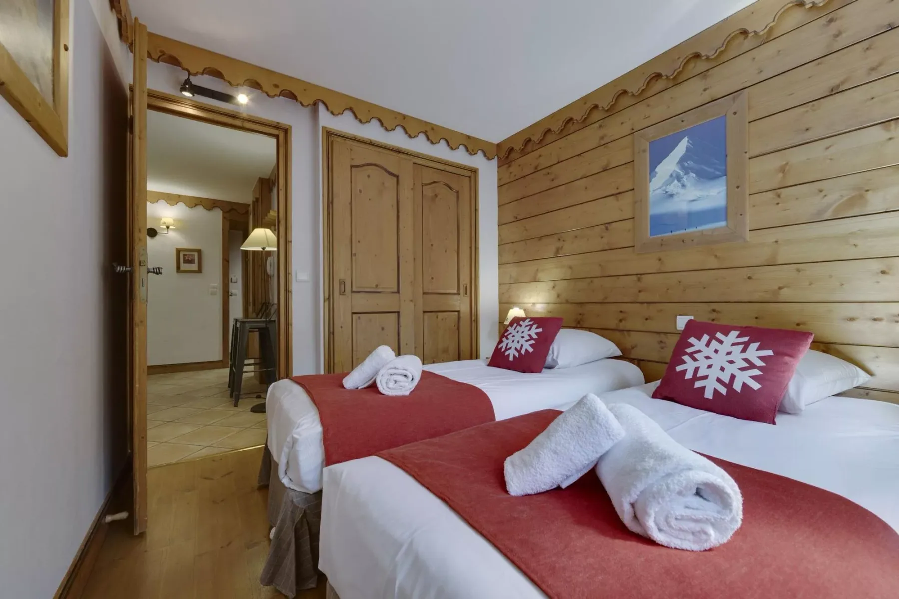 Un dormitorio con dos camas, cubrecamas rojos y cojines con motivos de copos de nieve.