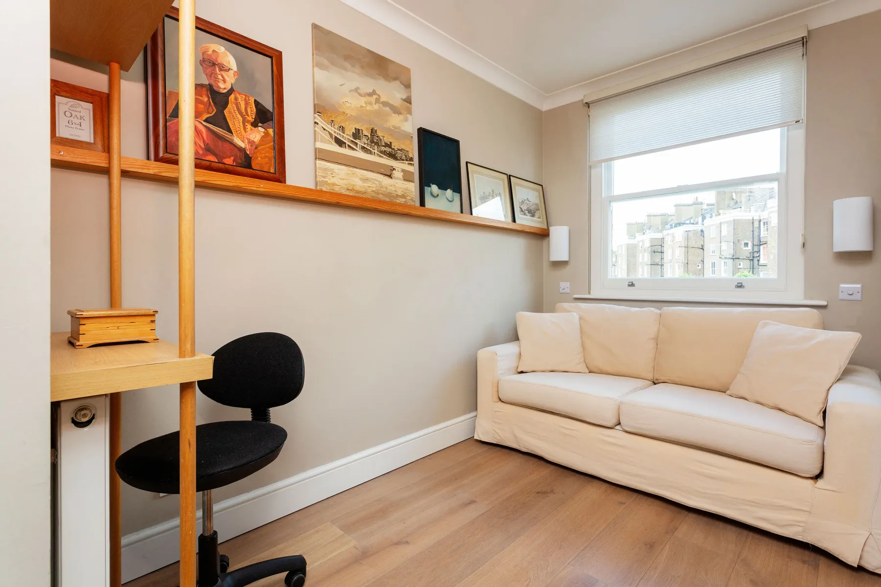 Una sala luminosa con asientos color crema, cuadros enmarcados y una ventana grande.