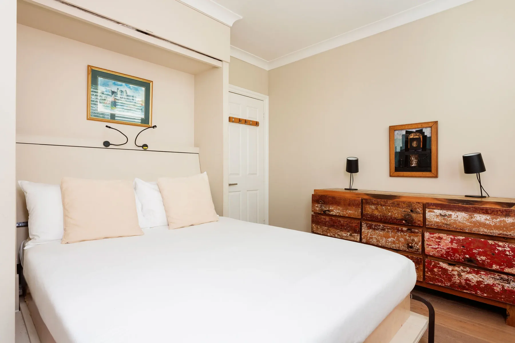 Un dormitorio luminoso con una cama bien tendida y una cómoda de madera.