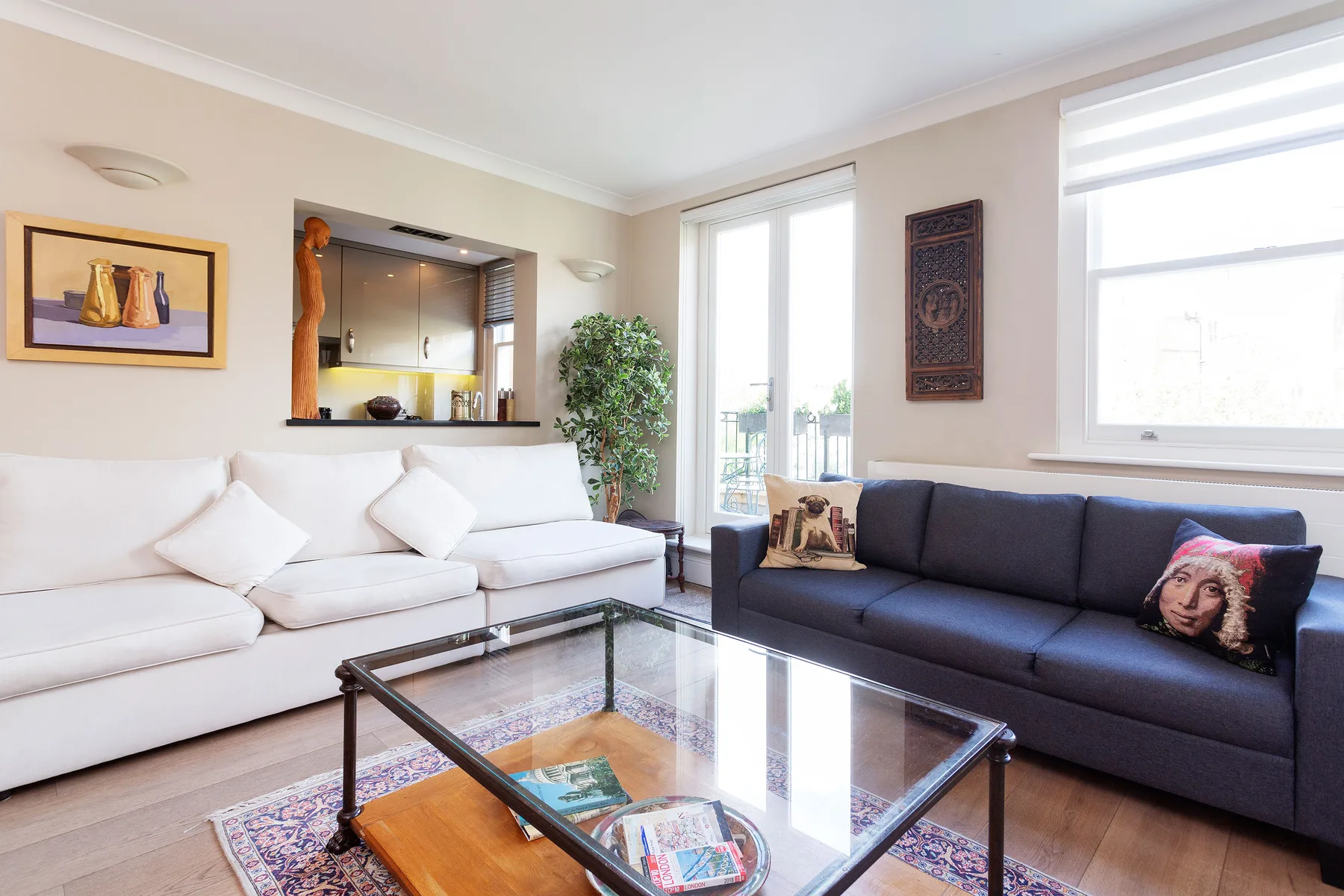 Sala de estar con asientos claros y oscuros alrededor de una mesa de centro de vidrio.