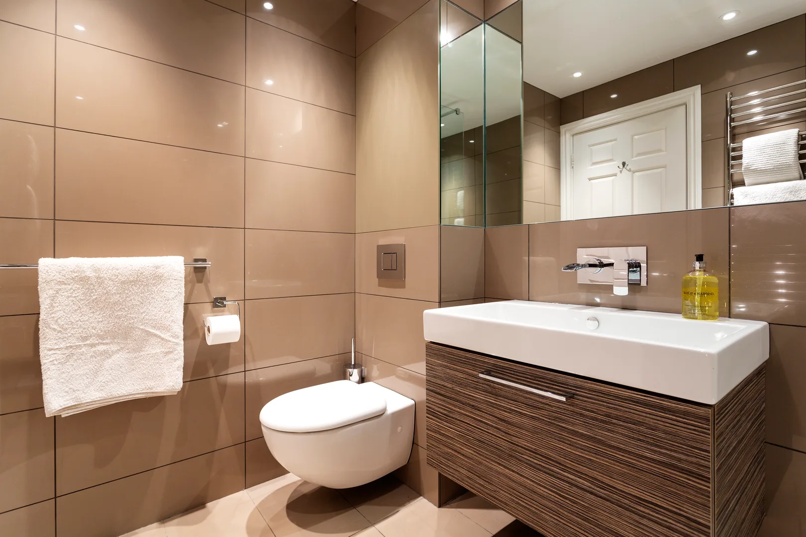 Un baño con azulejos, un inodoro suspendido y un lavabo con mueble.