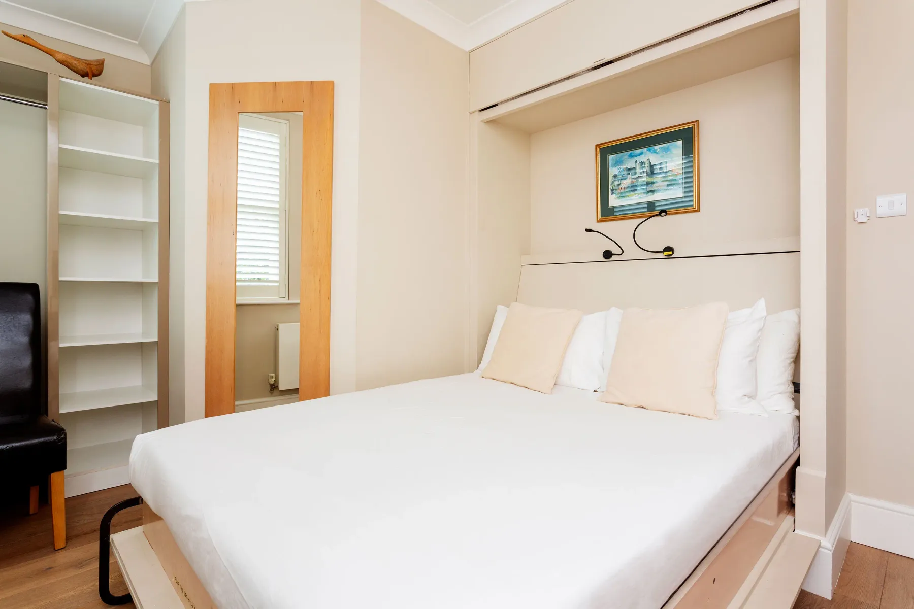 Dormitorio con una cama bien tendida y un cuadro enmarcado encima.