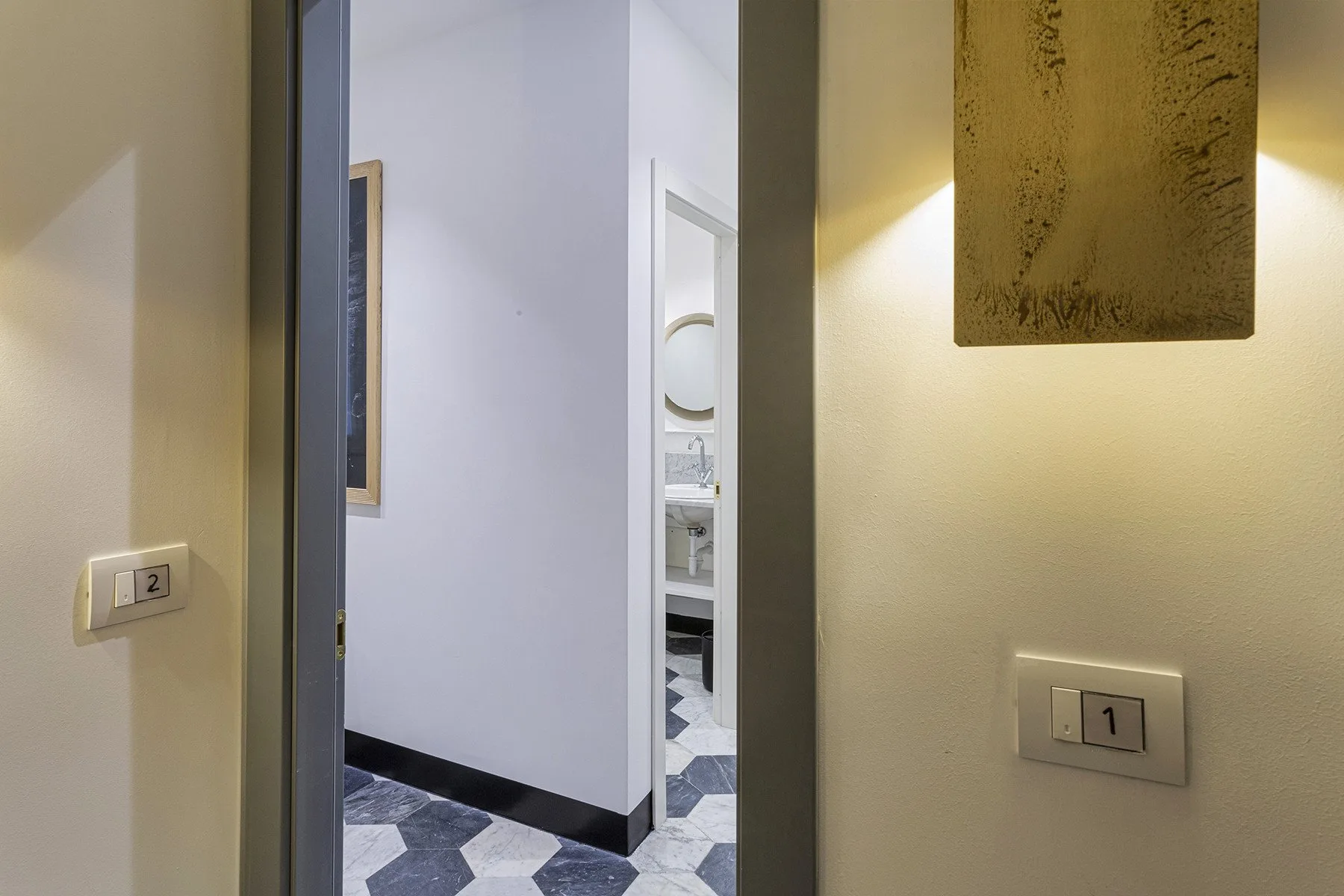 A hallway opens onto a bright bathroom with patterned floor tiles.
