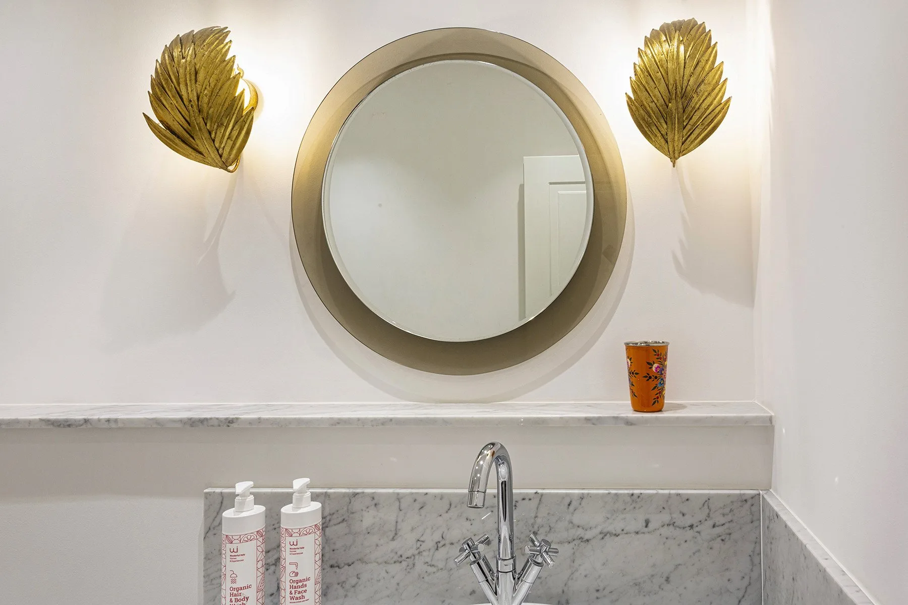 A bathroom vanity with a round mirror above a marble-patterned sink.