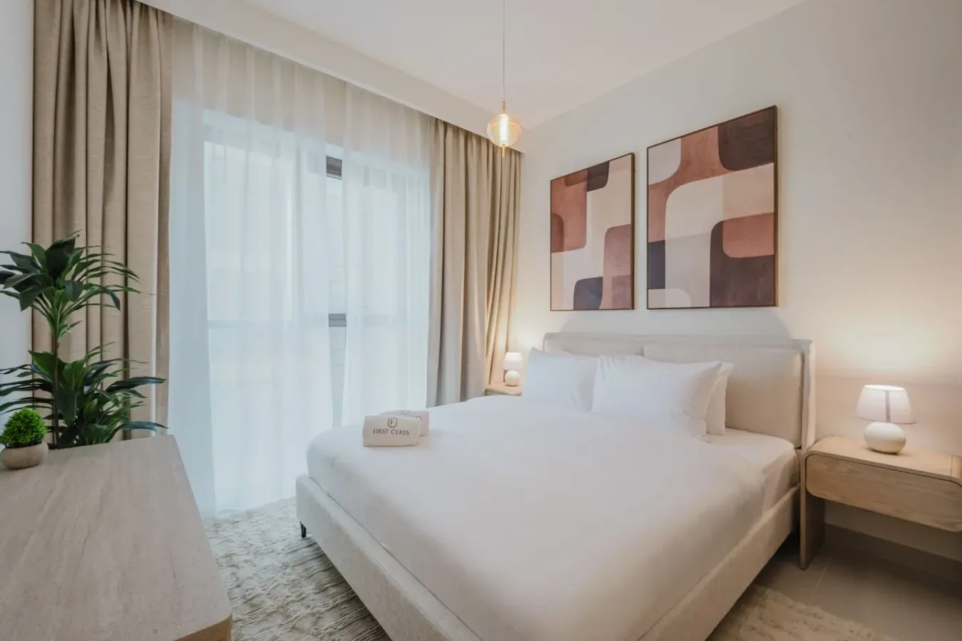 A bright bedroom with a neatly made bed and abstract wall art.