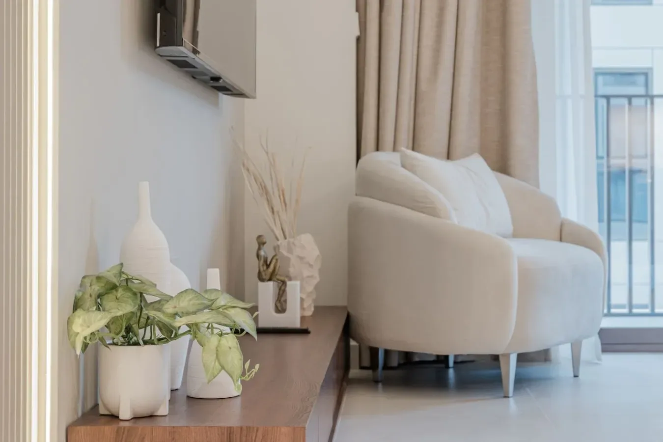 A bright living room with a pale sofa beside a low wooden table.