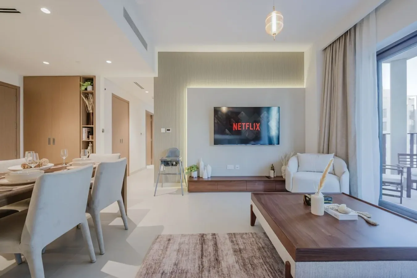 A bright living and dining area with a wall-mounted television and seating.
